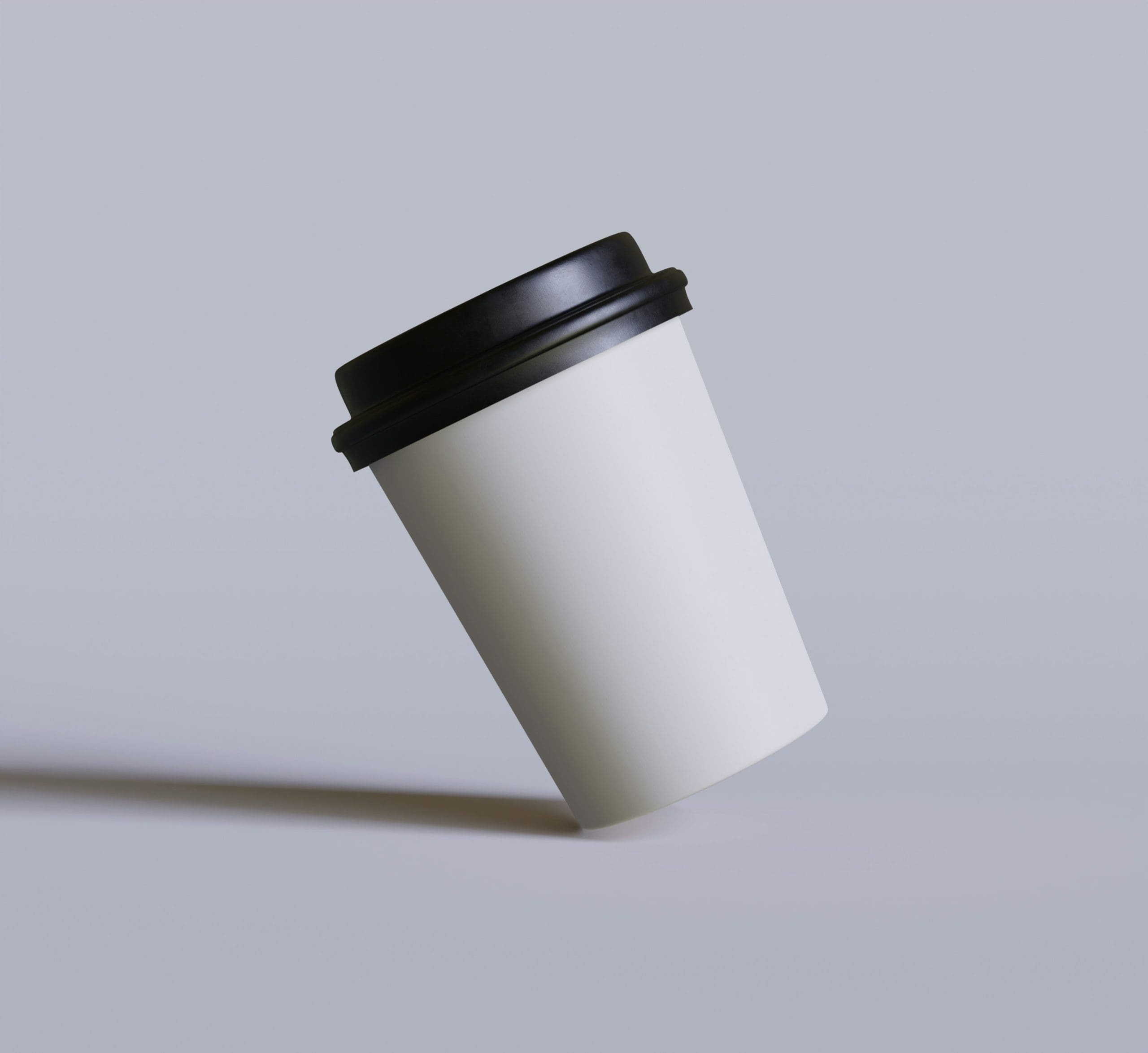 White coffee cup with a black lid, angled and casting a shadow, symbolizing the convenience of takeout beverages.