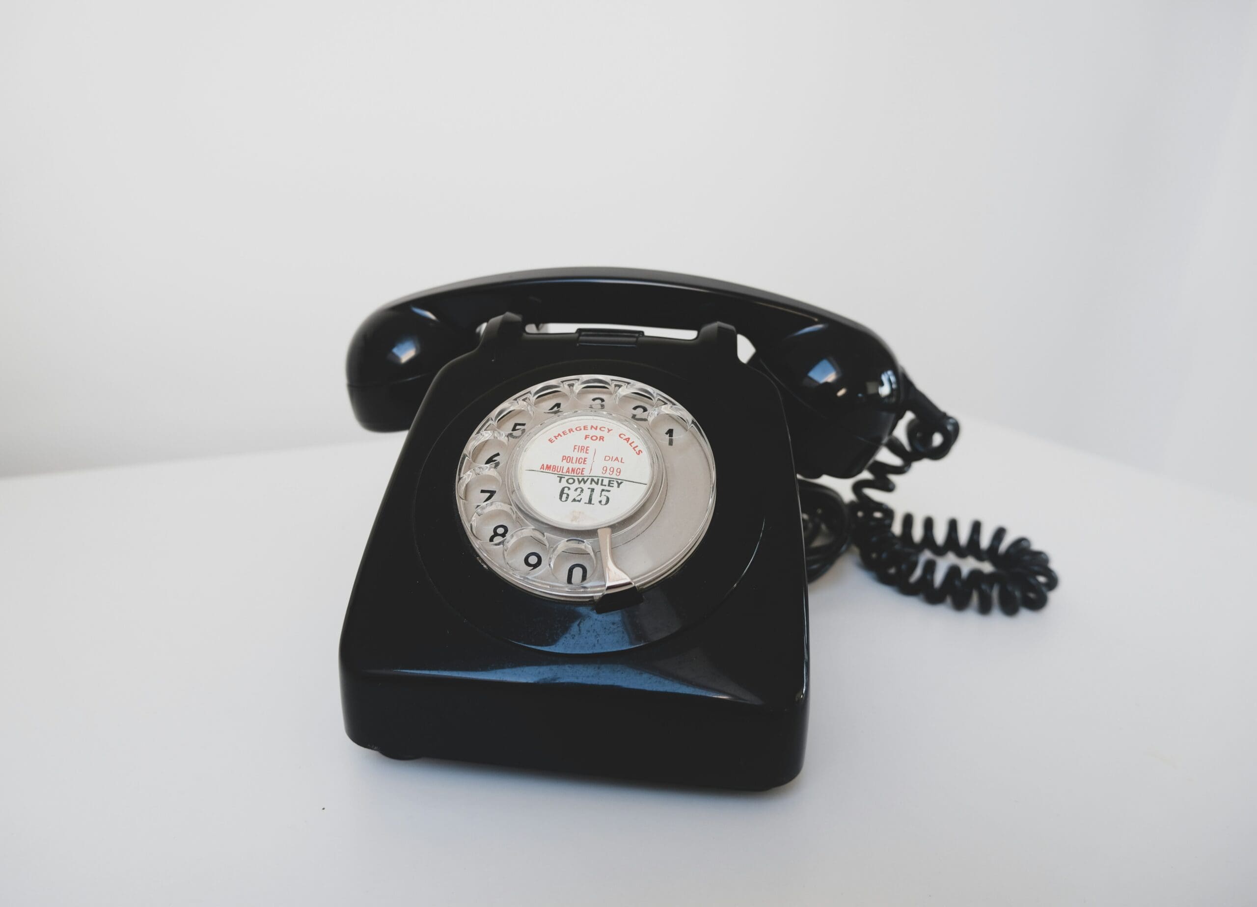 Vintage black rotary telephone on a white surface, symbolizing traditional communication methods in business telecoms.