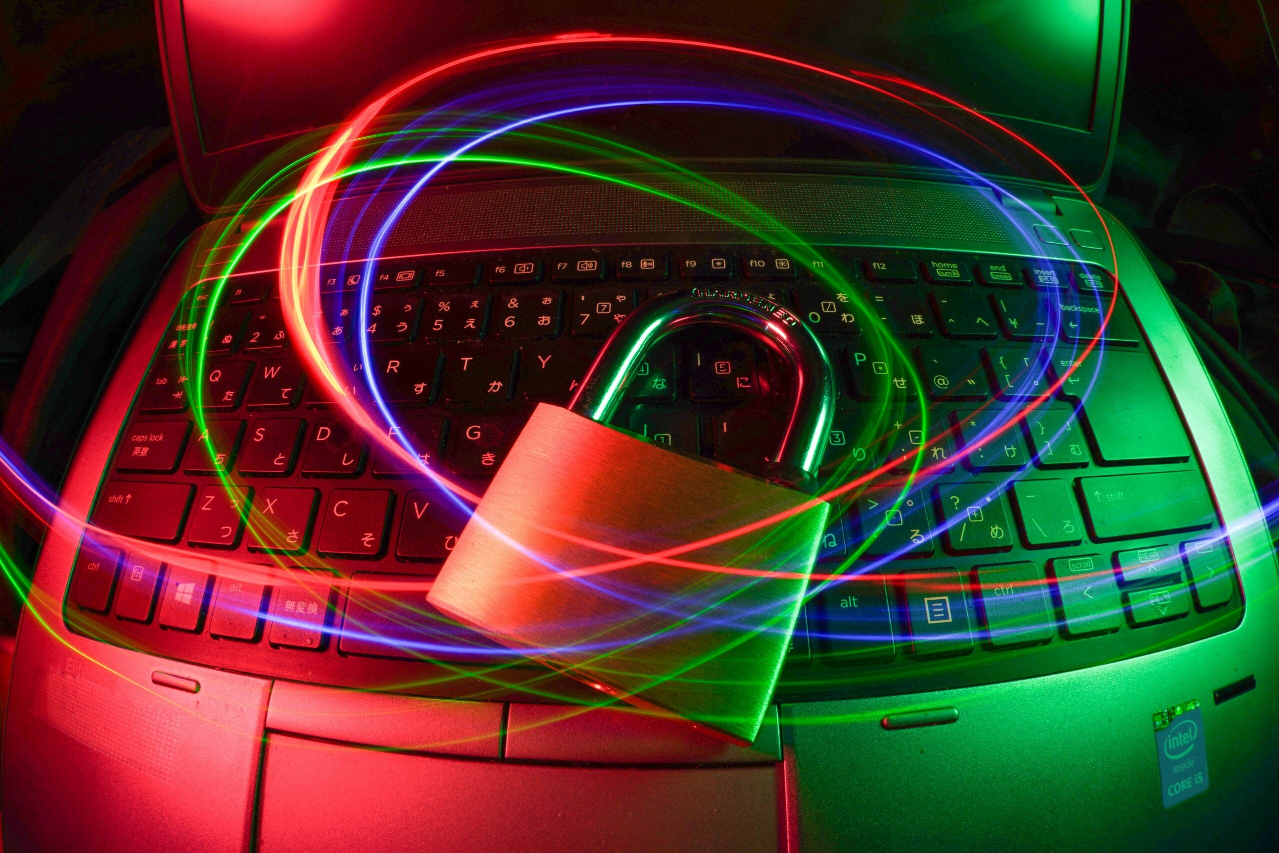 Padlock on a laptop keyboard with colorful light trails, symbolizing cybersecurity and digital protection in 2025.