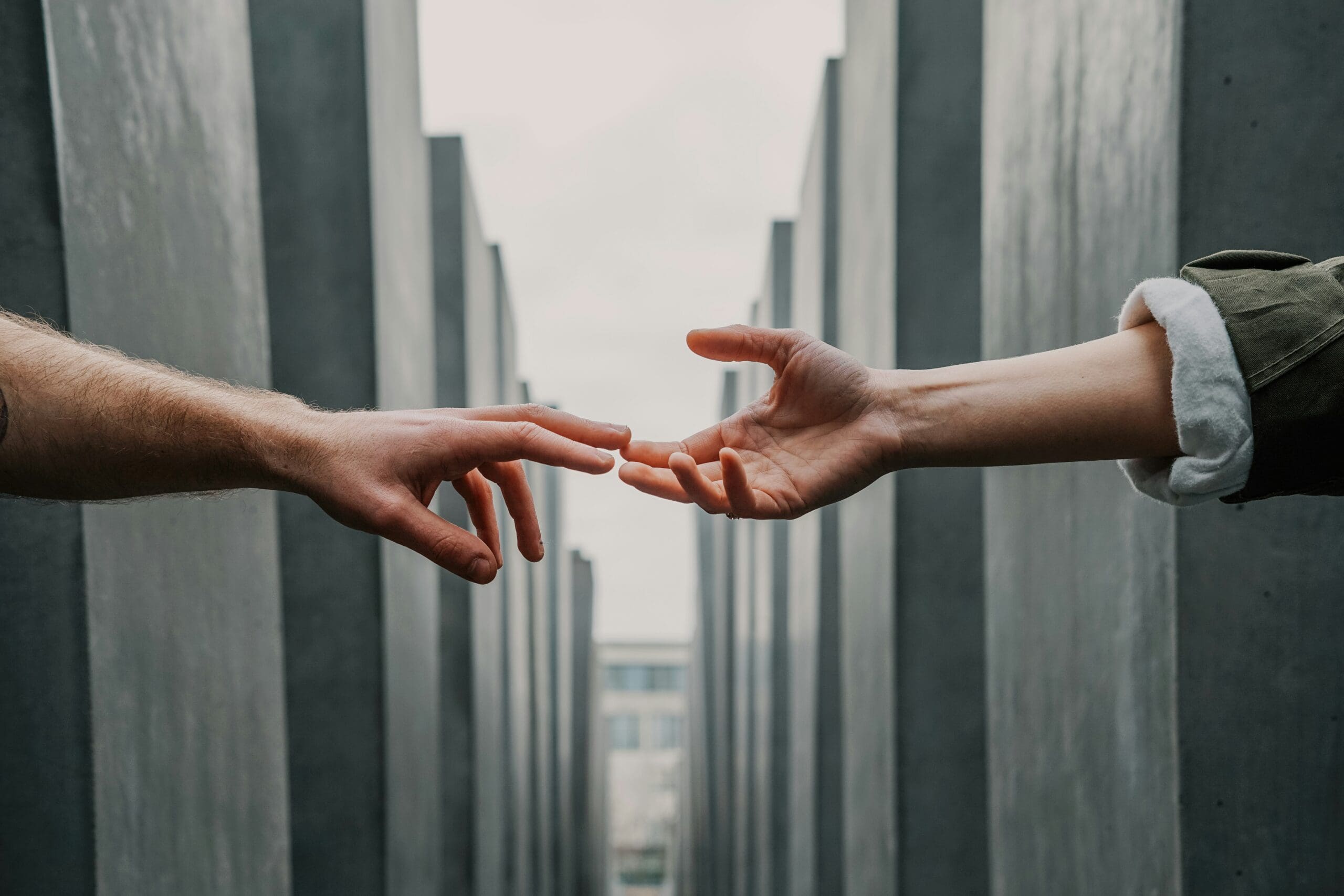 Hands reaching toward each other in a concrete corridor, symbolizing connection and support, relevant to IT managed support and enhancing customer service.